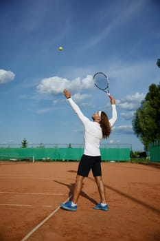 Young male tennis player engaged in training on outdoor sports court. Man in sportswear hitting ball with racket
