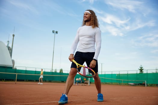 Happy smiling male tennis player wearing trendy outfit ready for morning workout on outdoor court