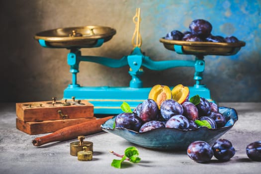 Fresh plums on plate over dark stone background
