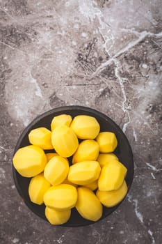 Raw peeled potatoes in a bowl on kitchen table