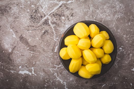 Raw peeled potatoes in a bowl on kitchen table