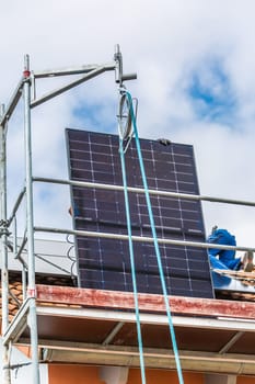 Lifting solar panels using pulley. Installing solar panels on a roof. Solar panels on roof. Workers installing solar cells.