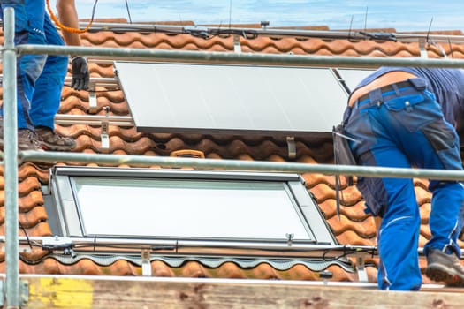 Installing solar panels on a roof. Solar panels on roof. Workers installing solar cells.