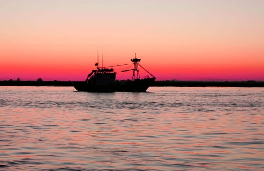 Fishing boat leaving port at nightfall. Fishing industry in andalusian coast, Spain