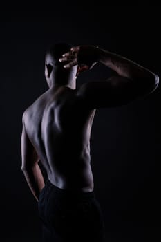 Athletic african american man topless, big muscles, a dark background studio
