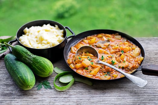 Eating Slovenian traditional dish with cucumber sauce in red and mashed potatoes. Freshly picked cucumbers from the garden. Summer food