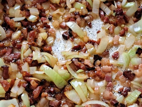 Speck und Zwiebeln bruzeln in einer Pfanne