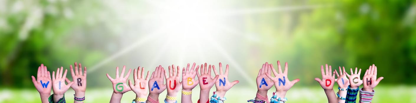 Children Hands Building Colorful German Word Wir Glauben An Dich Means We Believe In You. Sunny Green Grass Meadow As Background.