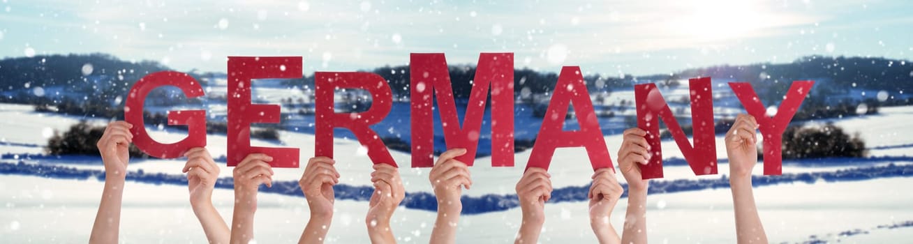 People Or Persons Hands Building English Word Germany. White Winter Background With Snowflakes And Snowy Landscape.