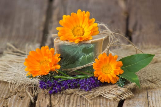 Natural handmade soap with calendula, lavender and herbs on rustic wooden background