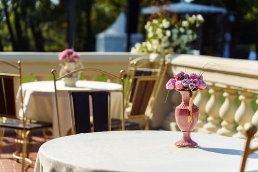 The tables are decorated with vases of fresh flowers on the outdoor terrace of the restaurant.
