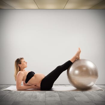 Pregnant woman does fitness exercises with ball