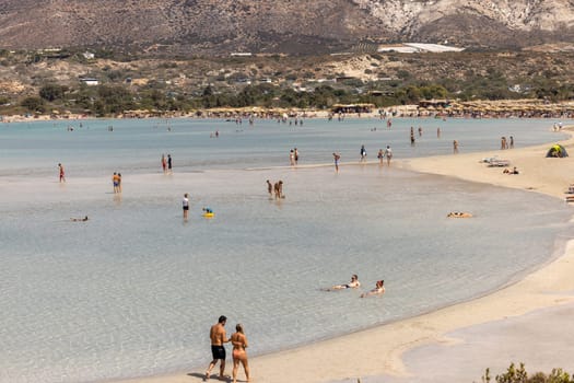 Elafonisi, Crete, Greece - Sept 19, 2021: People relaxing on the famous pink coral beach of Elafonisi on Crete, Mediterannean sea, Greece