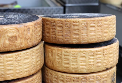 Cremona, Italy - September 7, 2022: Whole wheels of Monte Veronese cheese sold at a street stall during the farmers market in Cremona, Lombardy, Italy