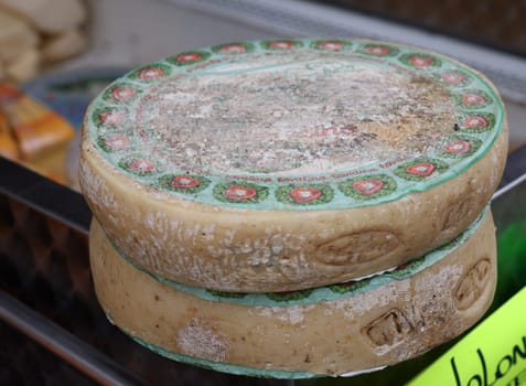 Cremona, Italy - September 7, 2022: Whole wheels of Parmigiano Lovatino cheese sold at a street stall during the farmers market in Cremona, Lombardy, Italy