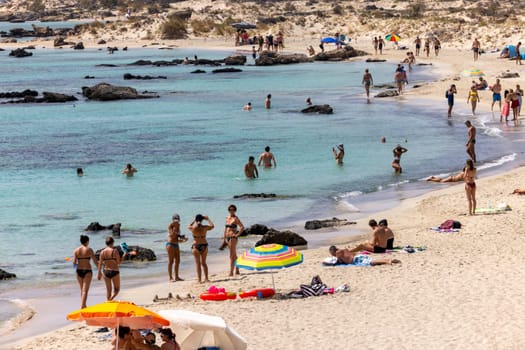 Elafonisi, Crete, Greece - Sept 19, 2021: People relaxing on the famous pink coral beach of Elafonisi on Crete, Mediterannean sea, Greece