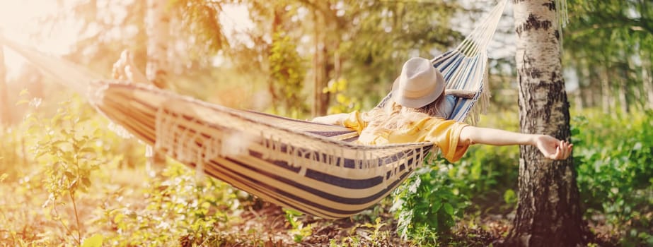Woman lying in the hammock with hat on her face. Beautiful panoramic background.