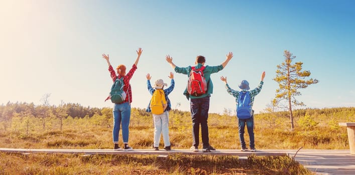 Family standing on the nature with rising nands. Concept of the freedom, tourism and hiking.