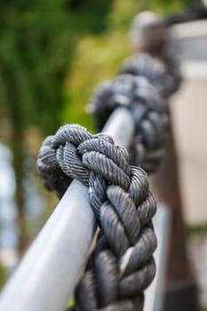 Perspective view along a railing with a plastic rope leading into the blur.