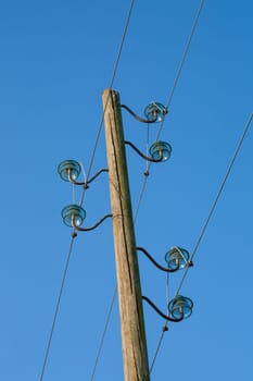 A wooden electric pole, on a blue background with the moon in the background.