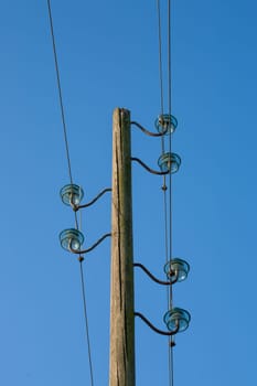 A wooden electric pole, on a blue background with the moon in the background.