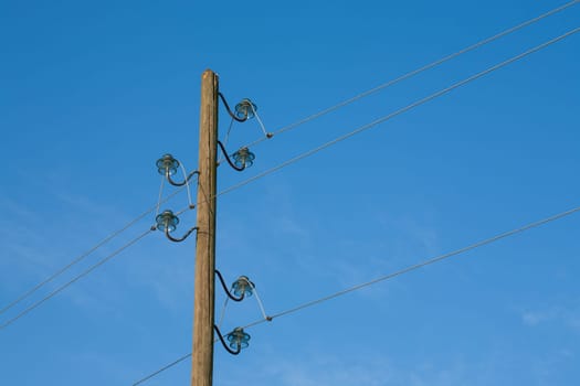A wooden electric pole, on a blue background with the moon in the background.