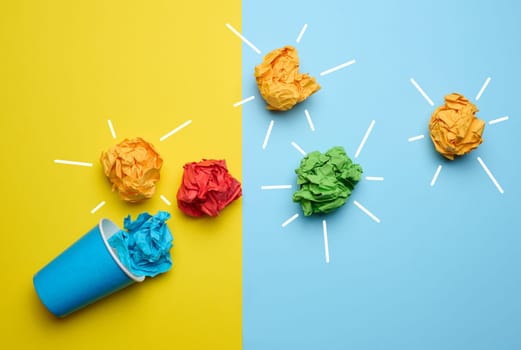 The concept of inspiration with new ideas, the search for creative solutions, crumpled sheets of paper in the form of balls on a blue yellow background
