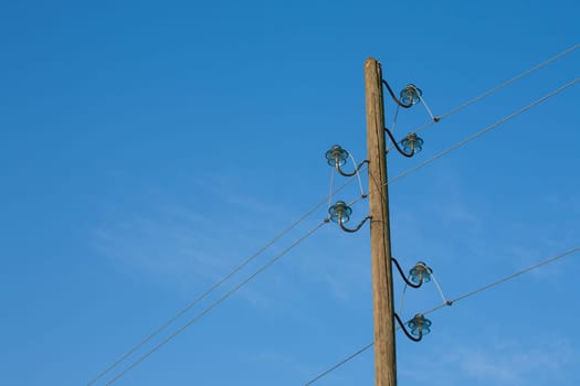 A wooden electric pole, on a blue background with the moon in the background.