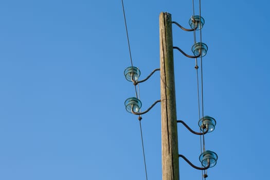 A wooden electric pole, on a blue background with the moon in the background.