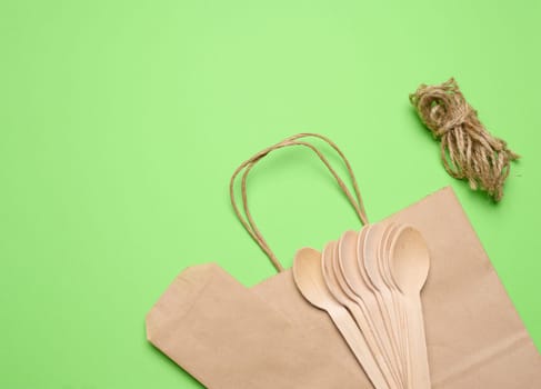 Wooden spoons, paper bag and tow rope on a green background, top view