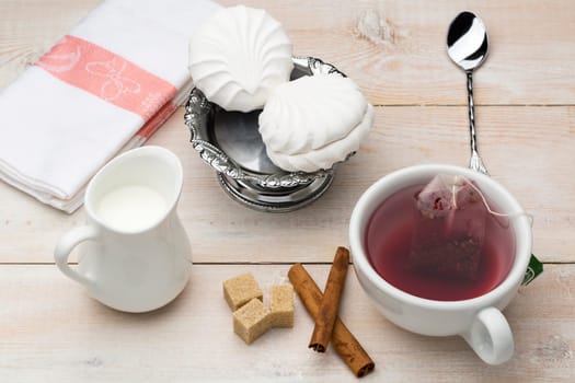 Set of cup red tea and dessert on bright wooden table
