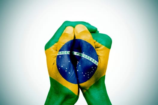closeup of the hands of a young man put together patterned with the flag of Brazil against a white background, with a slight vignette added