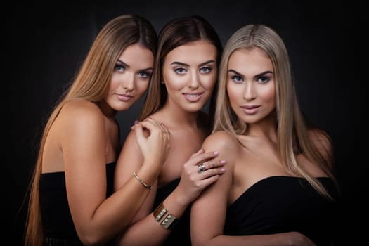 Three sexy girls in casual clothes posing on dark background