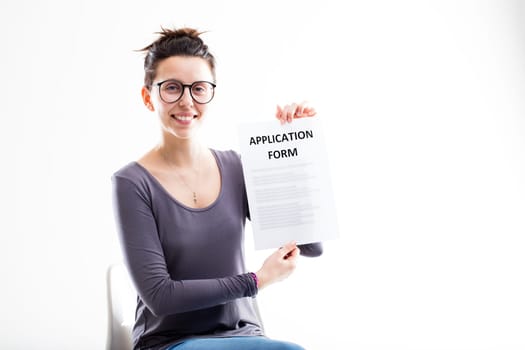 woman with glasses showing an application form and smiling sitting on a white office chair