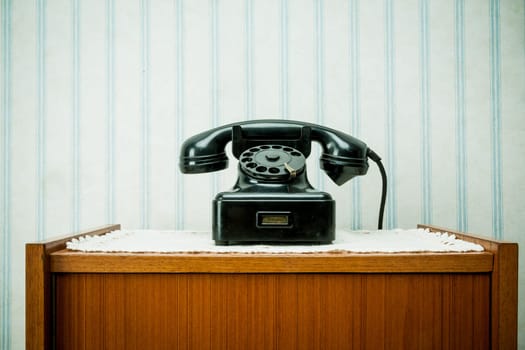 old-style image of a vintage telephone on a night table over a doily