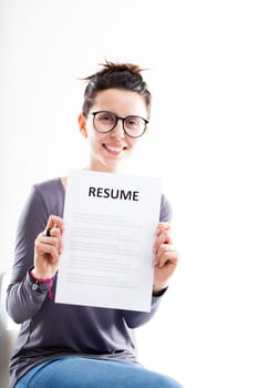 smiling woman with glasses sat on a white chair showing a resume