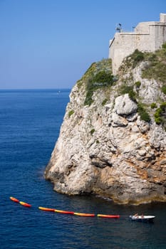Dubrovnik, Croatia - June 27, 2023: Transportation of colorful kayaks for tourists by water on the Adriatic Sea to the West Harbour next to Fort Lovrijenac and City Walls