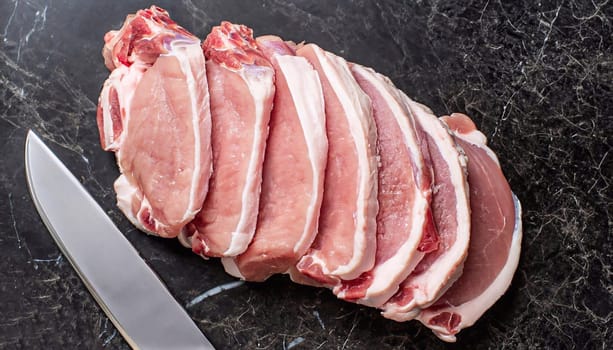 Sliced raw pork meat with meat knife on dark background