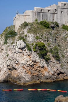 Dubrovnik, Croatia - June 27, 2023: Transportation of colorful kayaks for tourists by water on the Adriatic Sea to the West Harbour next to Fort Lovrijenac and City Walls