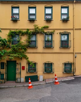 Facade of residential building with walls painted in orange and green, with wrought iron window and climber plants, at an alley suited in Kuzguncuk neighborhood, Uskudar district, Istanbul, Turkey