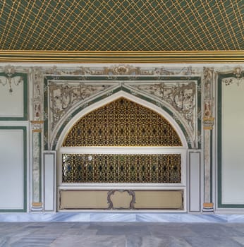 Golden decorated wrought iron arched windows in painted ornate wall and green decorated ceiling at the courtyard of Dolmabahce Palace, Besiktas district, Istanbul, Turkey