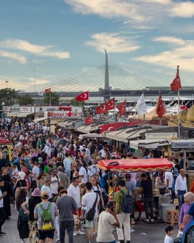 Istanbul, Turkey - August 30, 2022: Crowds of local citizens at Eminonu Plaza during the Victory Day holiday with background of Istanbul city view including Golden Horn Metro Bridge
