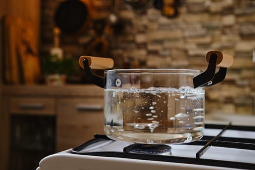 Water boiling in transparent glass pot on stove