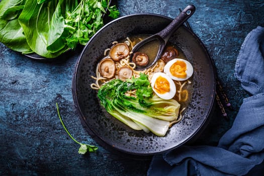 Miso ramen Asian noodles soup with shiitake, egg and pak choi cabbage on dark background