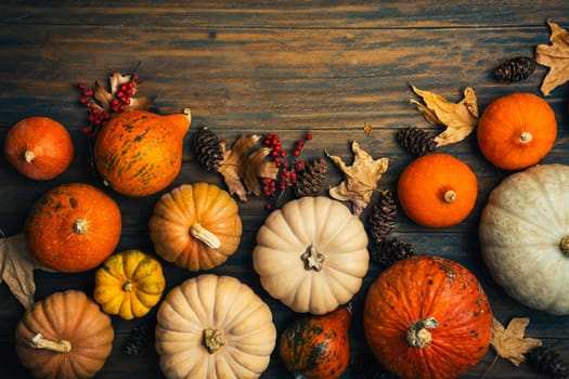 Thanksgiving and autumn background decoration with different pumpkins and dried leaves on wooden background