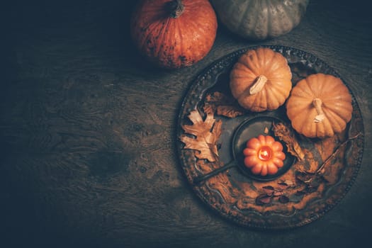 Autumn or fall harvest concept with pumpkins and candles on dark wooden background