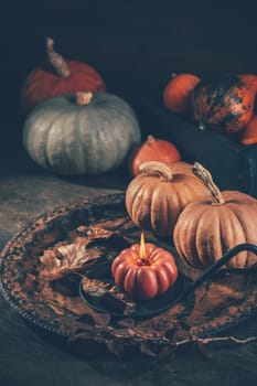 Autumn or fall harvest concept with pumpkins and candles on dark wooden background