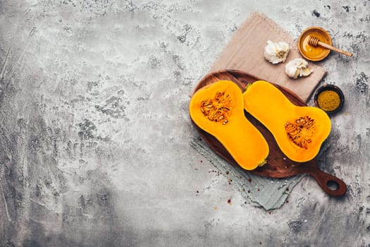 Halves of raw organic butternut squash with spices and ingredients for cooking