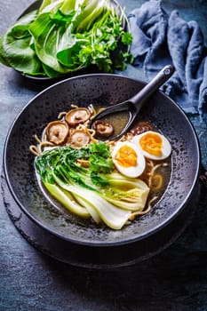 Miso ramen Asian noodles soup with shiitake, egg and pak choi cabbage on dark background