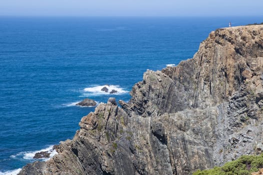 Visitors observing the sea from the top of cliff of Cabo Sardao coast, Ponta do Cavaleiro, Sao Teotonio, Portugal